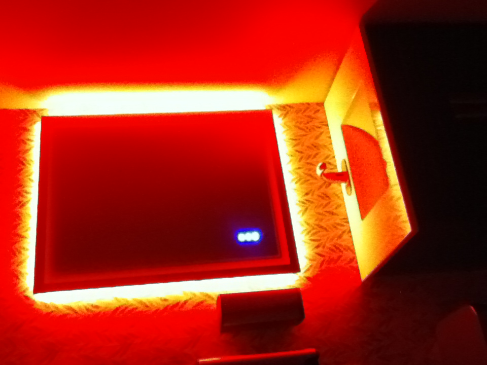 A bathroom sink and backlit mirror, the whole room blown out to saturated red